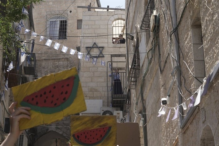 FILE - Jewish girls watch Israelis and Palestinians holding pictures of watermelon, a Palestinian symbol, as they protest the imminent eviction of a Palestinian family by a Jewish settler organization outside their home in the Muslim Quarter of the Old City of Jerusalem, June 16, 2023. Watermelons have emerged on banners, t-shirts, cars and social media over the past three months in protests against the Israel-Hamas war. From New York and Tel Aviv to Dubai and Belgrade, the fruit has caught on globally as a symbol of solidarity with the Palestinian people.