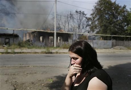 A local woman sits and cries in front of her burning house after shelling in Donetsk, eastern Ukraine, Sunday, Sept. 7, 2014. 