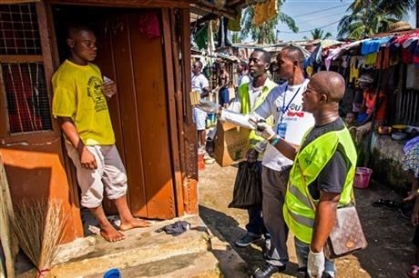 Health worker volunteers talk to a resident to distribute bars of soap and information about Ebola in Freetown, Sierra Leone, Saturday, Sept. 20, 2014.