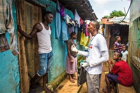 A health worker volunteer talks with a resident on how to prevent and identify the Ebola virus in others, and distributes bars of soap in Freetown, Sierra Leone, Saturday, Sept. 20, 2014. 