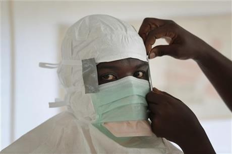 An MSF nurse is prepared with Personal Protection Equipment before entering a high risk zone of MSF's Ebola isolation and treatment centre.