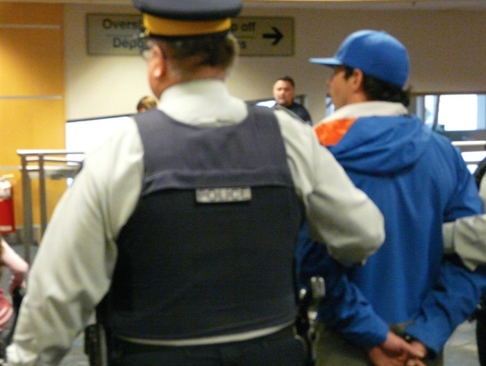 A person of interest is taken into custody at the Kelowna Airport, Saturday, Oct. 25, 2014.