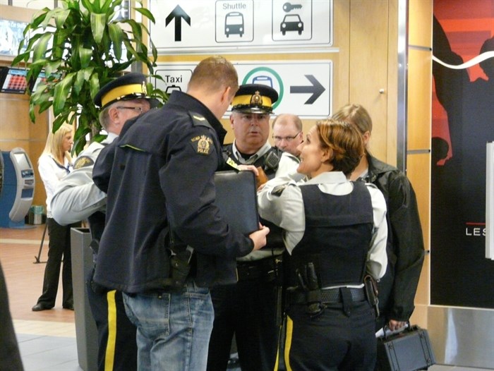 Members of the RCMP investigate a threat against a WestJet flight at the Kelowna Airport, Saturday, Oct. 25, 2014.