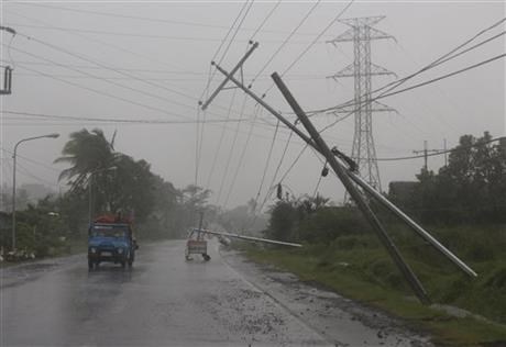 Motorists pass by toppled electrical posts during Typhoon Hagupit in the Philippines, Sunday, Dec. 7, 2014.