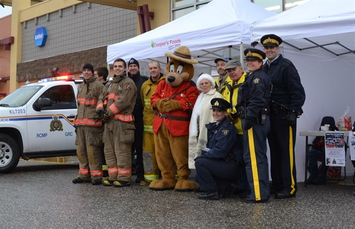 Lake Country Fire Fighters, RCMP officers and auxiliary constables and RCMP volunteers are pictured with Lake Country Food Bank manager Phyllis MacPherson and the Sgt. Sam Brown mascot.