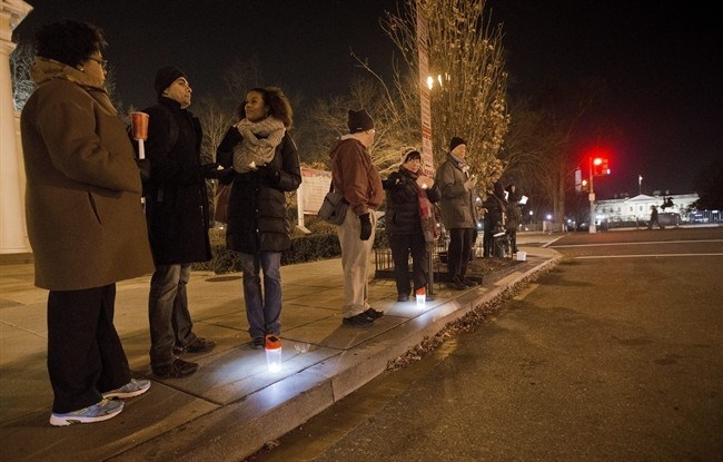 Participants stand on the curb holding candles or flashlights during a visual demonstration near the White House in response to the recent grand jury decisions not to indict police officers, Friday, Dec. 12, 2014, in Washington.