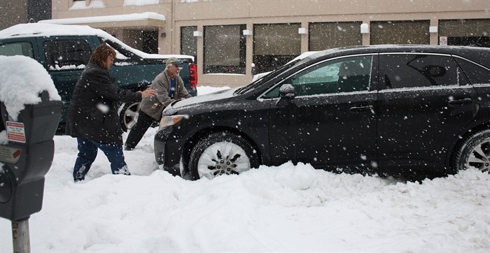 Harry and Bonnie Kinakin assist a motorist stuck in a parking stall in front of Penticton City Hall, Monday, Jan. 5, 2015.