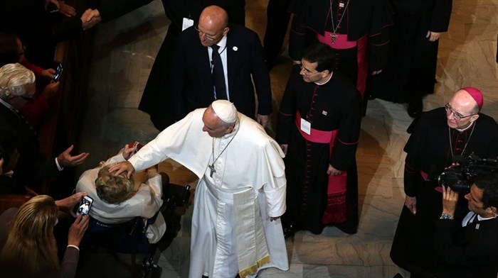 Pope Francis touches a woman in a wheelchair after he addressed a gathering in Saint Martin's Chapel at St. Charles Borromeo Seminary Sunday, Sept. 27, 2015.