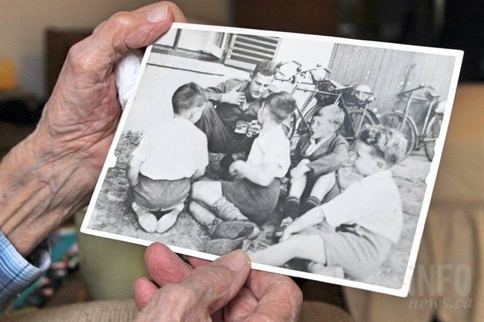 Ford holds his favourite picture from the war. It's from when he was visiting with some children outside a pub in England. The photo ended up in the Province newspaper and his mother cut it out to save for him.