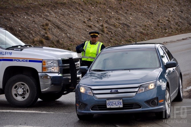 An RCMP officer directs a local resident around a roadblock at the entrance to the neighbourhood where the bodies of a man and woman were found.