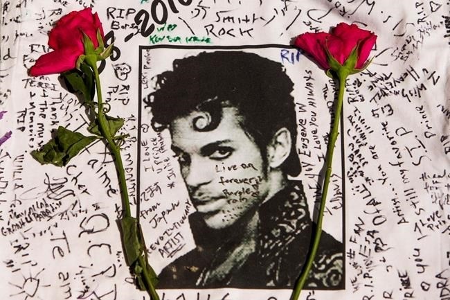 Flowers lay on a T-shirt signed by fans of singer Prince at a makeshift memorial place created outside Apollo Theater in New York, Friday, April 22, 2016. The pop star died Thursday at the age of 57.
