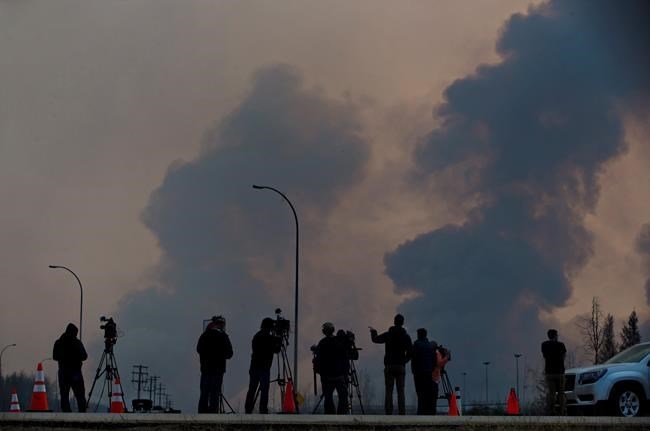 Media watch as smoke billows in the sky near a wildfire in Fort McMurray, Alta., on Friday, May 6, 2016.