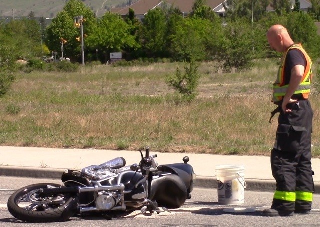 A Kelowna firefighter looks at a motorbike involved in a collision on Baron Rd.