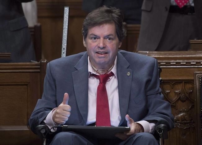 Ottawa-Vanier MP Mauril Belanger gives the thumbs up as he receives applause after using a tablet with text-to-speech program to defend his proposed changes to neutralize gender in the lyrics to 