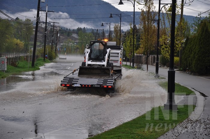 Work crews arrive to begin remediation work on Gellatly Road, covered by floodwaters.