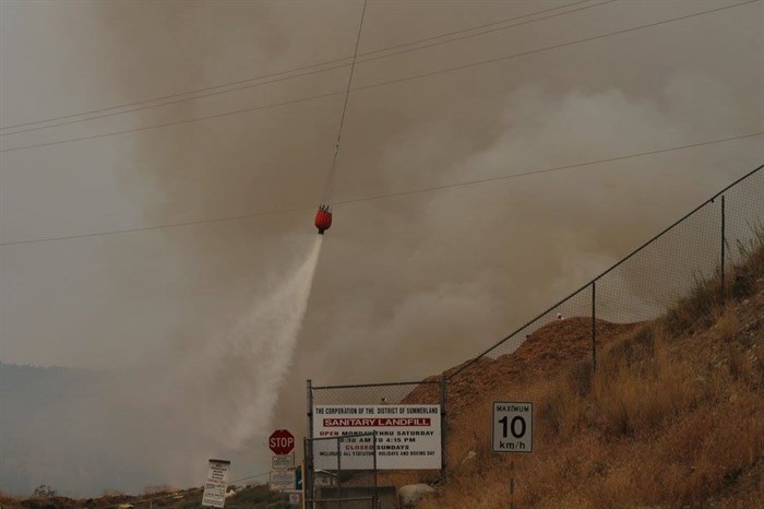 A helicopter buckets a fire at the Summerland landfill, Wednesday, Aug. 30, 2017.