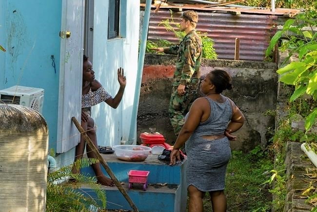 Two local women chat as a Dutch Marine helps out in preparation for the arrival Hurricane Maria, in Oranjestad, Statia, on the Leeward Islands, Monday, Sept. 18 2017. Maria has intensified into a Category 5 hurricane as its eye is approaching Dominica in the eastern Caribbean, the U.S. Hurricane Center said in a statement on Monday evening.