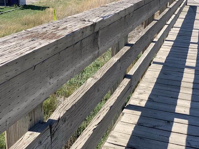 The railings on the sides of the Pritchard Bridge are made of wood and a raised wooden sidewalk runs along one side.