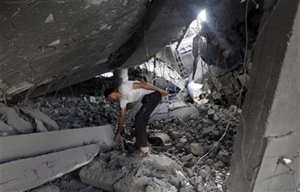 A Palestinian searches the ruins of the Al-Tawfeeq mosque after it was hit by an Israeli missile strike Saturday, July 12, 2014.