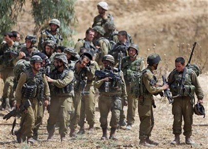 Israeli infantry soldiers get ready to walk to their armored personnel carriers to take up new positions on the Israel-Gaza border, Saturday, July 12, 2014.
