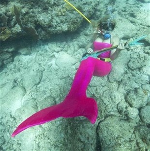 Samantha Langsdale, costumed as a mermaid, pretends to play a mock musical instrument at the Lower Keys Underwater Music Festival on Saturday, July 12, 2014.