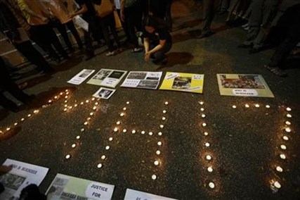A woman looks at newspaper cuttings at a candlelight vigil for the victims of Malaysia Airlines Flight 17 in Kuala Lumpur, Malaysia, Saturday, July 19, 2014.