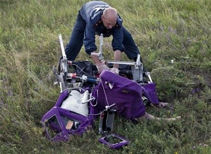 An emergency worker cuts through aircraft seat belts to free the body of a victim at the crash site of Malaysia Airlines Flight 17 in eastern Ukraine, Saturday, July 19, 2014.