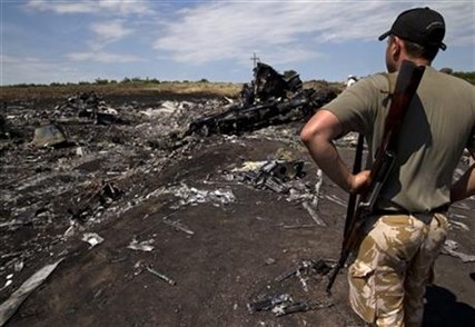An armed man looks at charred debris at the crash site of Malaysia Airlines Flight 17 in eastern Ukraine, Sunday, July 20, 2014.
