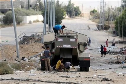 Palestinian men climb on Israel's military vehicle that was left behind by the forces in Gaza City's Shijaiyah neighborhood, Saturday, July 26, 2014.