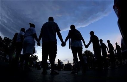 People stand in prayer on Wednesday, Aug. 20, 2014, in Ferguson, Mo.