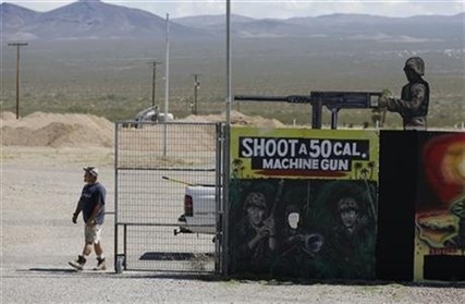 A man closes off an entrance to the Last Stop outdoor shooting range Wednesday, Aug. 27, 2014, in White Hills, Ariz.