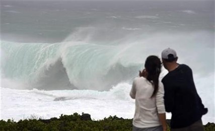 A couple watches a huge wave at a cape in Yomitan Village, Japan's southern island of Okinawa Sunday, Oct. 12, 2014.