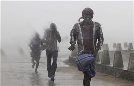 People run for shelter as heavy rain and wind gusts rip through the Bay of Bengal in India, Sunday, Oct. 12, 2014.