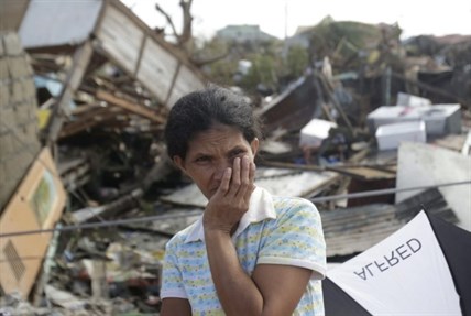 A survivor stands outside her damaged house at typhoon ravaged Tacloban city, Leyte province, central Philippines on Monday, Nov. 11, 2013. Authorities said at least 2 million people in 41 provinces had been affected by Friday's disaster and at least 23,000 houses had been damaged or destroyed.