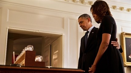 President Barack Obama and first lady Michelle Obama take a moment of silence in honor of the Newtown shooting victims on the one year anniversary of the tragedy, in the Map Room of the White House in Washington, Saturday, Dec. 14, 2013.