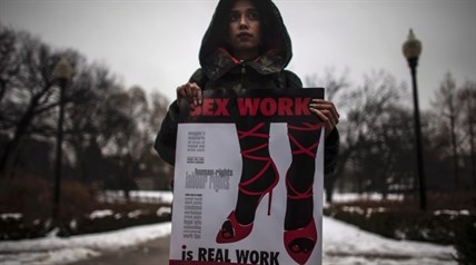 A woman (requested to withhold her name) holds a sign during a rally at Allan Gardens park to support Toronto sex workers and their rights in Toronto, Friday December 20, 2013.