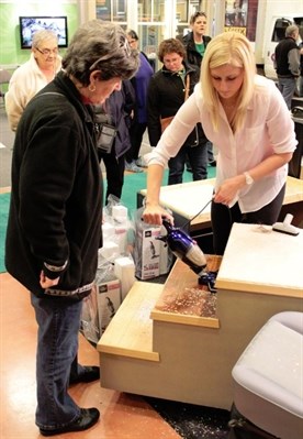 Donna Mitansky of Penticton watches Jessica Pleysier vacuum up a combination of wood chips and glitter at the Canadian Home Builders' Association South Okanagan 18th annual Home and Renovation Show. Mitansky soon bought herself one of the units.