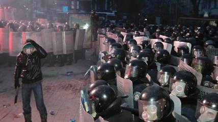A protester stands in front of riot police in central Kiev, Ukraine, Sunday, Jan. 19, 2014.