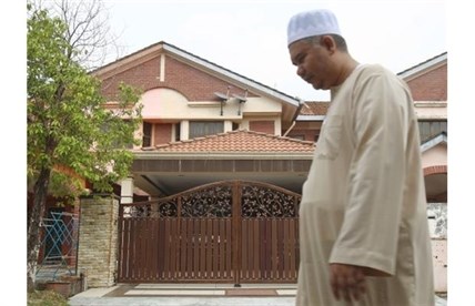 A Muslim man walks past the missing Malaysia Airlines co-pilot Fariq Abdul Hamid’s house after a prayer in Shah Alam, outside Kuala Lumpur, Malaysia, Saturday, March 15, 2014. 