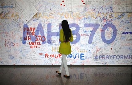 A woman reads messages and well wishes to people involved with the missing Malaysia Airlines jetliner MH370, Saturday, March 15, 2014 in Sepang, Malaysia.