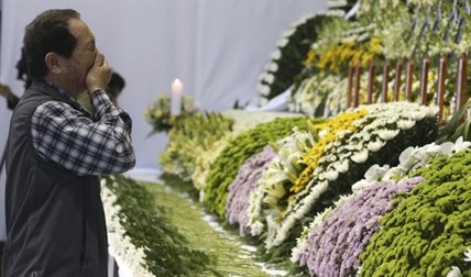 A mourner weeps as he pays tribute to the victims of the sunken ferry Sewol in the water off the southern coast at a gymnasium, in Ansan, South Korea, Wednesday, April 23, 2014. 