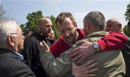Russia's presidential human rights ombudsman Vladimir Lukin, left, and members of foreign military observers, German Col. Axel Schneider, second from left, watch other members hug at each other following their release in Slovyansk, eastern Ukraine, Saturday, May 3, 2014.