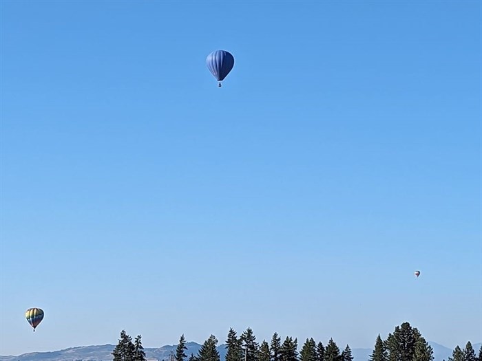 Three hot air balloons are seen floating over Armstrong. 