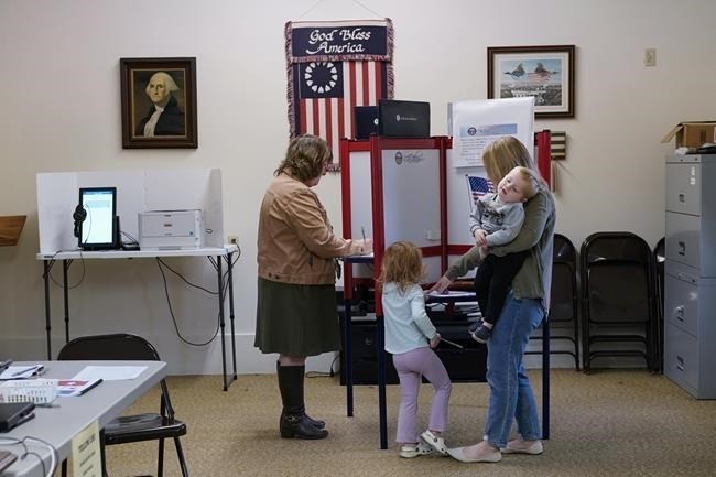 Lauren Miracle, right, holds her son Dawson, 1, as she helps her daughter Oaklynn, 3, fill out a child's practice ballot before voting herself at a polling location in the Washington Township House in Oregonia, Ohio, Tuesday, Nov. 7.
