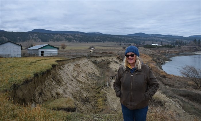 Wendy Robertson stands in front of part of her pasture that his since fallen into the North Thompson River.