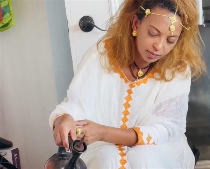 Vernon resident Azeb Gemechu pouring a traditional Ethiopian coffee ceremony wearing an Ethiopian dress called a ye Habesha kemis.