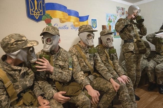 Cadets practice putting on gas masks during a lesson in a bomb shelter in a cadet lyceum in Kyiv, Ukraine, Tuesday, June 6, 2023. Writing on the wall reads: "Glory to Ukraine".