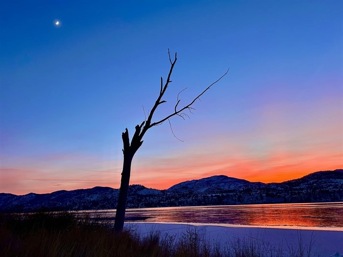 Blue sky, crescent moon and orange sunset captured over Skaha Lake, Penticton. 