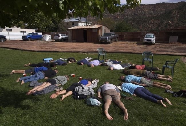 FILE - Participants lay face down on the grass during an integration circle at an ayahuasca retreat in Hildale, Utah, on Saturday, Oct. 15, 2022. Following each of the three ayahuasca ceremonies, Hummingbird Church asks their participants to partake in integration, or a group reflection and discussion, to help interpret messages they received from the ayahuasca.