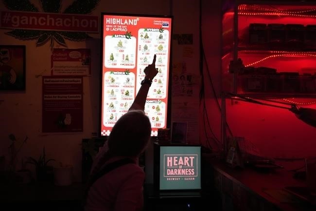 A customer watches menu of marijuana at Highland cafe shop in Bangkok, Thailand, Monday, Feb. 12, 2024. Thailand almost two years ago spawned a highly visible retail industry when it decriminalized the sale and possession of cannabis, but now appears set to tighten controls to ban its recreational use.